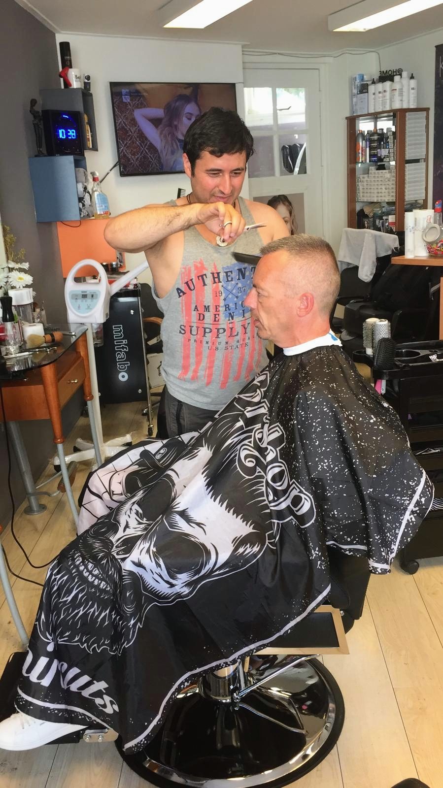 Kapper bij Yek aan het werk met schaar en kam bij een klant in de stoel
