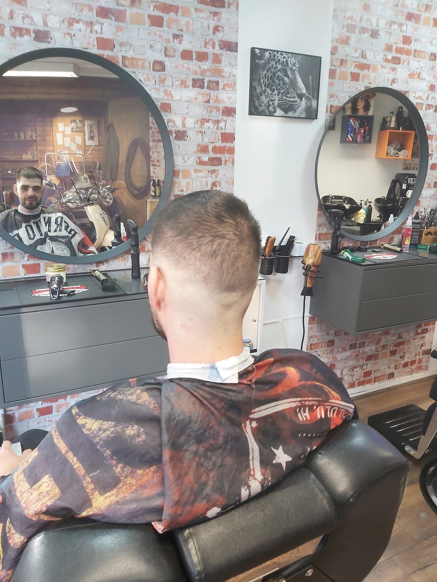 Klant van achteren met een strakke fade, richting de ronde spiegel